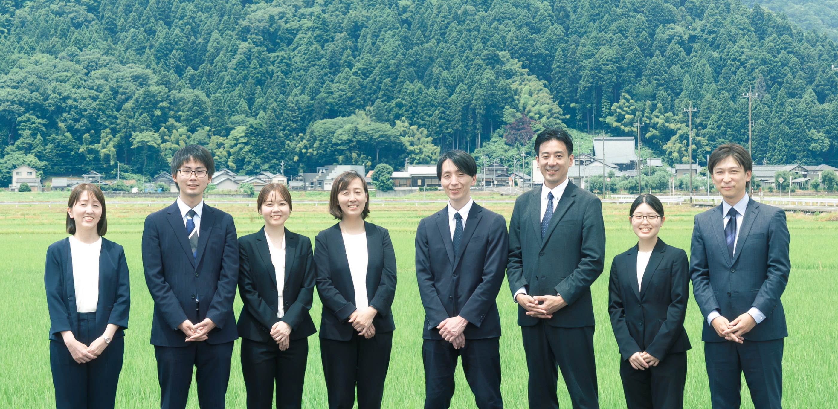 田園を背に並ぶ社員たち